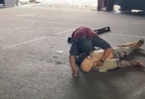 A man providing emergency care to a simulated patient on the ground.